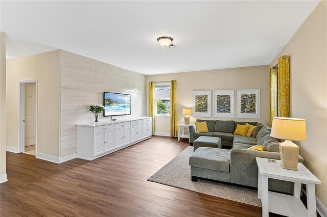 living area with baseboards, dark wood finished floors, and an accent wall