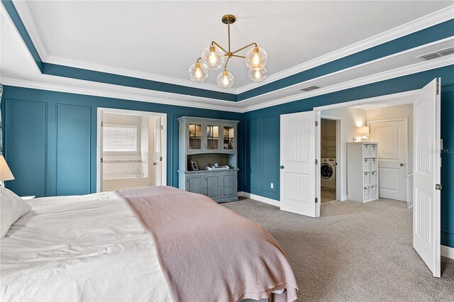 carpeted bedroom featuring visible vents, crown molding, an inviting chandelier, a decorative wall, and washer / clothes dryer