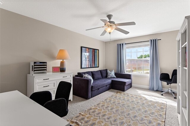 office with a textured ceiling, light carpet, baseboards, and ceiling fan