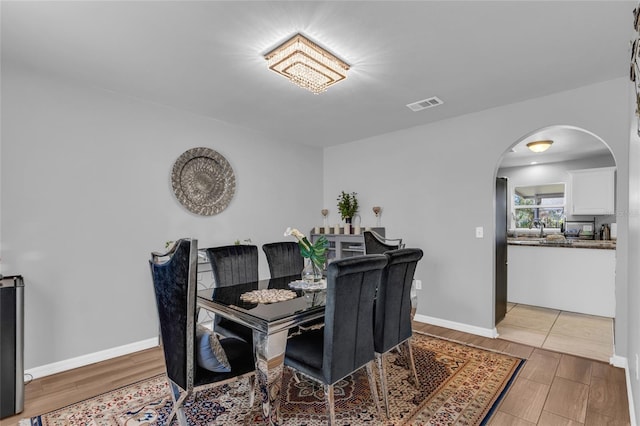 122 Carmel Bay Dr, Sanford, FL 32771 - dining area featuring visible vents, arched walkways, baseboards, and light wood finished floors