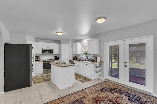 122 Carmel Bay Dr, Sanford, FL 32771 - kitchen with a kitchen island, french doors, appliances with stainless steel finishes, white cabinets, and light tile patterned flooring