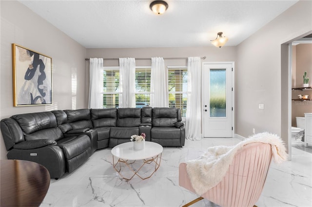 living room with baseboards, marble finish floor, and a textured ceiling