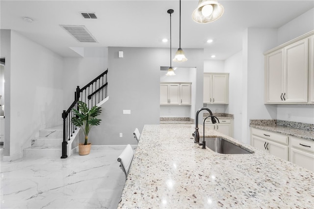 kitchen featuring pendant lighting, visible vents, marble finish floor, and a sink