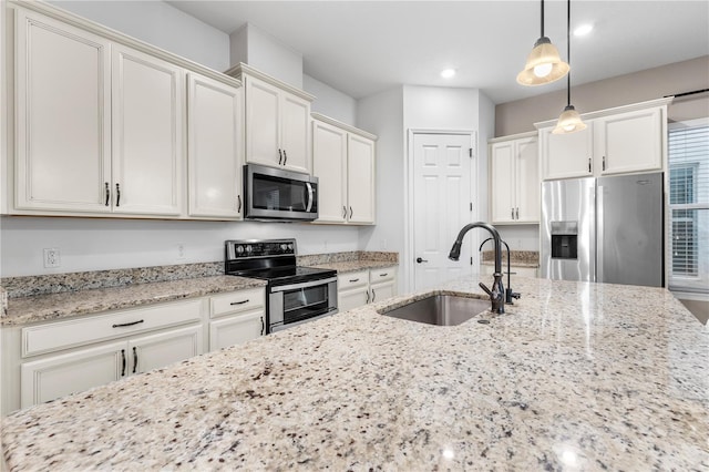 kitchen featuring light stone countertops, recessed lighting, a sink, stainless steel appliances, and pendant lighting