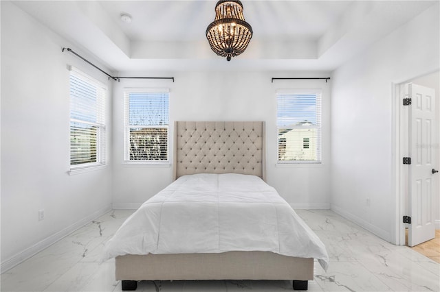 bedroom featuring baseboards, a raised ceiling, multiple windows, and marble finish floor