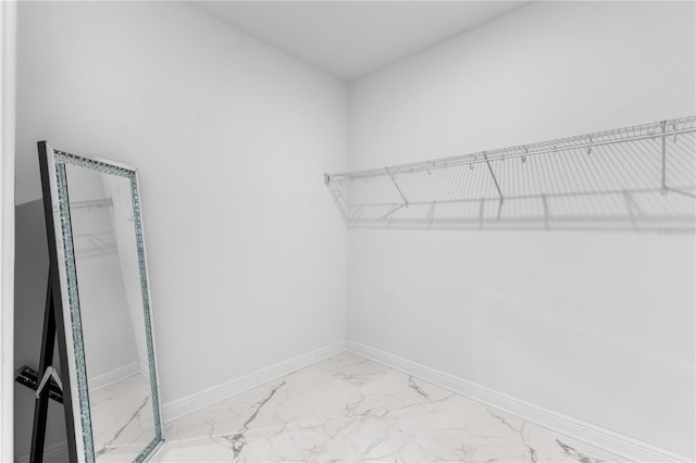walk in closet featuring marble finish floor