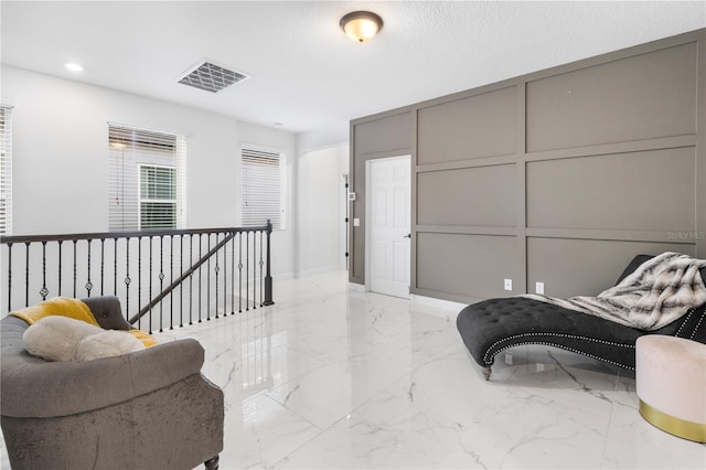 living area featuring visible vents, an upstairs landing, recessed lighting, a decorative wall, and marble finish floor