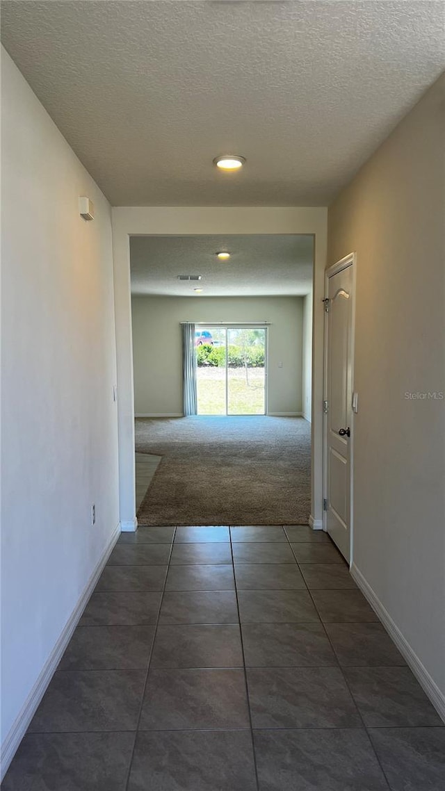 2597 Shamrock St, Tavares, FL 32778 - corridor featuring tile patterned flooring, visible vents, baseboards, carpet, and a textured ceiling