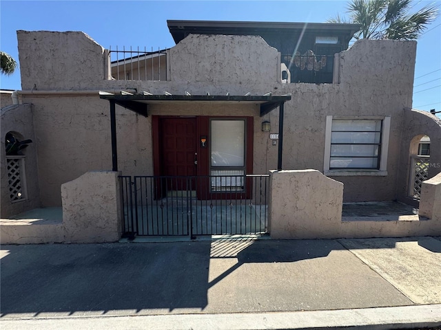 view of front facade featuring a gate, stucco siding, and fence