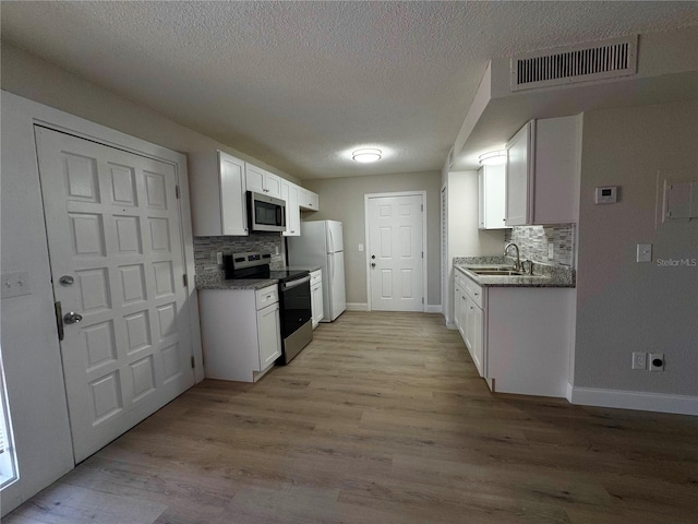 kitchen with visible vents, appliances with stainless steel finishes, light wood-style floors, white cabinetry, and a sink