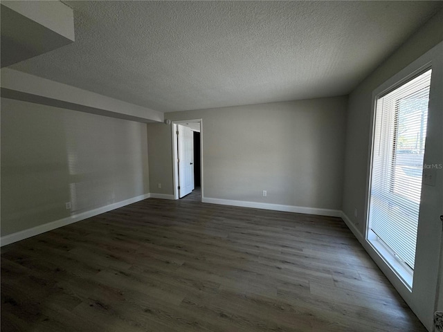 spare room with a textured ceiling, baseboards, and wood finished floors