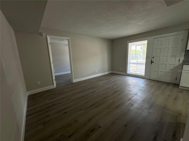 interior space with baseboards, a textured ceiling, and wood finished floors