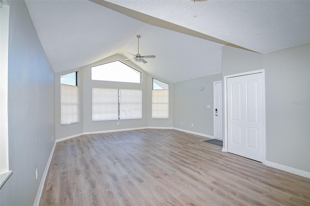 spare room featuring a ceiling fan, a textured ceiling, light wood-style floors, baseboards, and vaulted ceiling