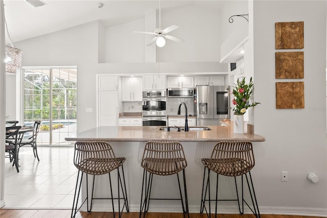 551 Wheatstone Pl, Orlando, FL 32835 - kitchen featuring appliances with stainless steel finishes, a peninsula, a kitchen bar, ceiling fan, and a sink