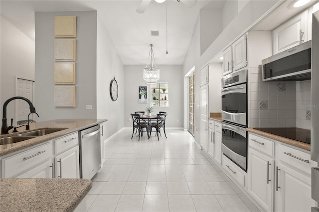 551 Wheatstone Pl, Orlando, FL 32835 - kitchen with tasteful backsplash, light tile patterned floors, white cabinets, appliances with stainless steel finishes, and a sink