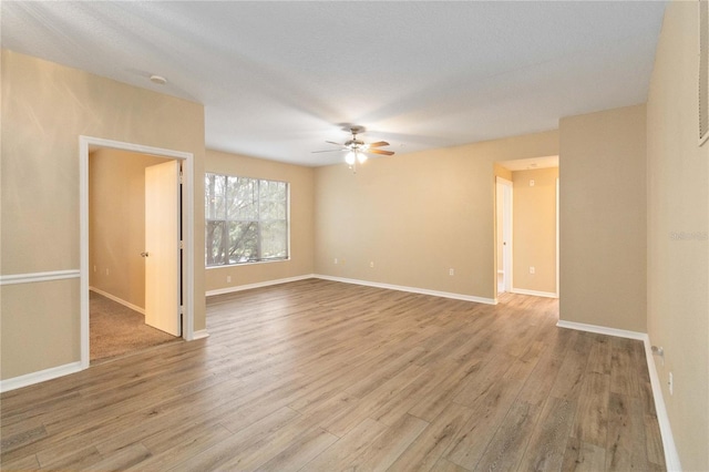 spare room featuring baseboards, wood finished floors, and a ceiling fan