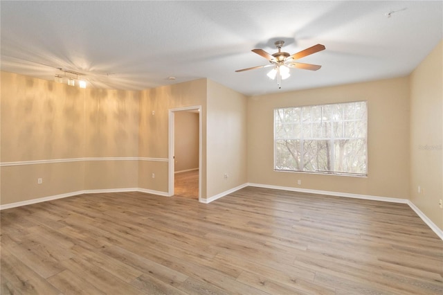 empty room with baseboards, a ceiling fan, and wood finished floors