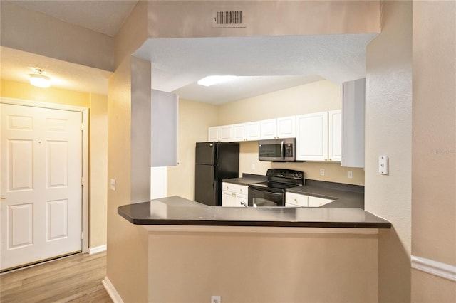 kitchen with dark countertops, visible vents, light wood-style flooring, white cabinets, and black appliances