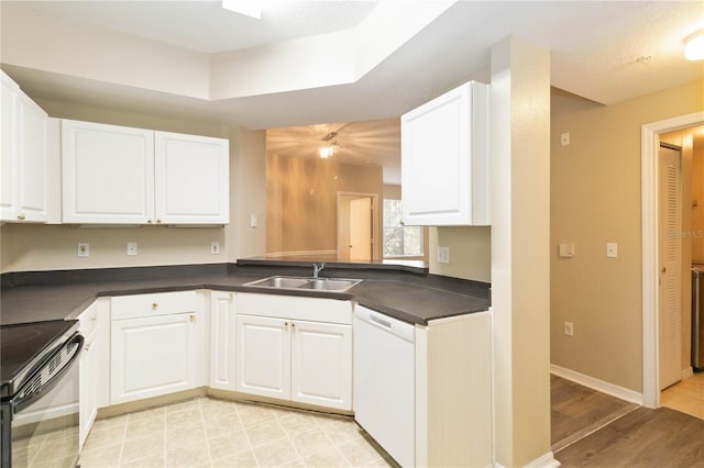 kitchen with white dishwasher, a sink, black range with electric cooktop, white cabinetry, and dark countertops