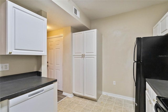 kitchen with stainless steel electric stove, white dishwasher, freestanding refrigerator, white cabinetry, and dark countertops