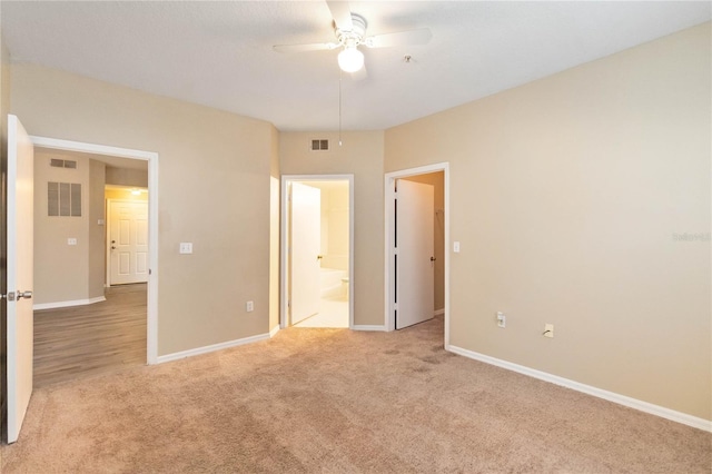 unfurnished bedroom featuring visible vents, light carpet, baseboards, and ensuite bath