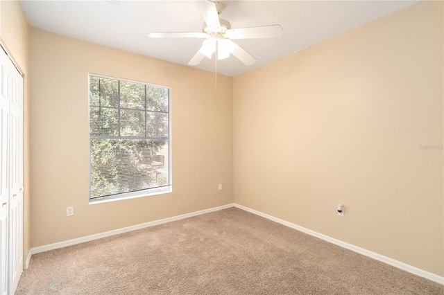 carpeted spare room featuring ceiling fan and baseboards