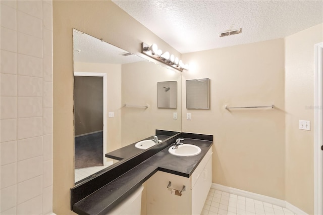 bathroom with tile patterned flooring, visible vents, baseboards, vanity, and a textured ceiling