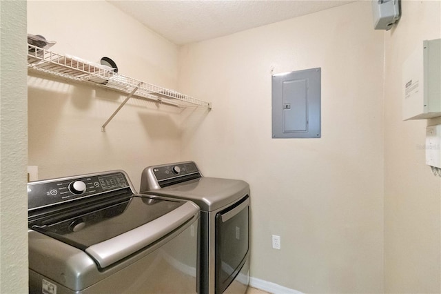 clothes washing area featuring electric panel, baseboards, laundry area, and washer and clothes dryer