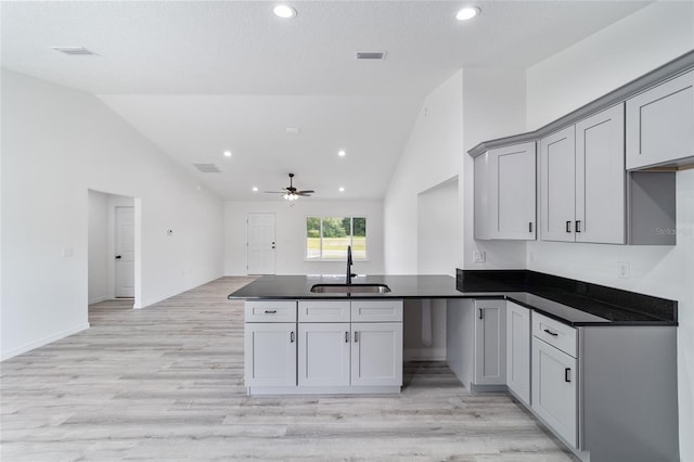 23741 SW Blueberry Ln, Dunnellon, FL 34431 - kitchen with a peninsula, dark countertops, a ceiling fan, light wood-type flooring, and gray cabinetry
