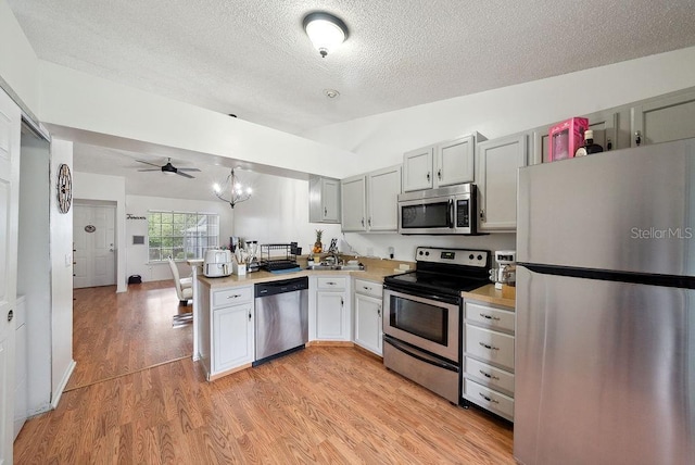 5417 Lake Margaret Dr Unit 39, Orlando, FL 32812 - kitchen featuring stainless steel appliances, a textured ceiling, light wood-type flooring, light countertops, and vaulted ceiling