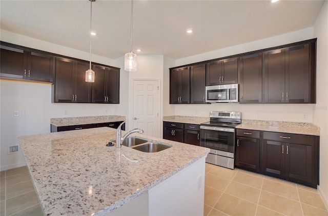 kitchen with light stone counters, dark brown cabinetry, appliances with stainless steel finishes, and a sink