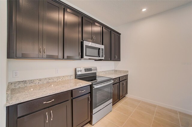 kitchen with recessed lighting, stainless steel appliances, baseboards, light tile patterned flooring, and light stone countertops