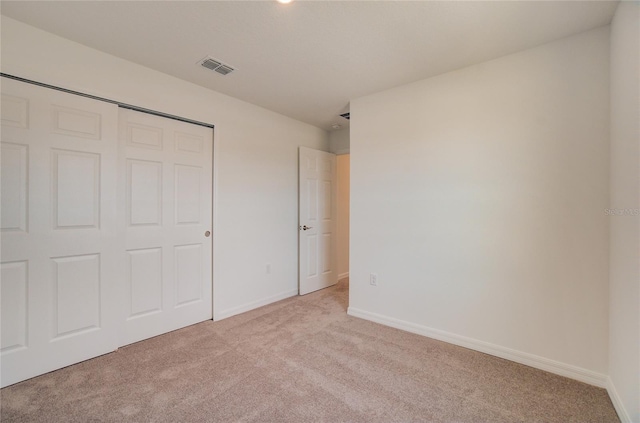 unfurnished bedroom featuring baseboards, light carpet, visible vents, and a closet