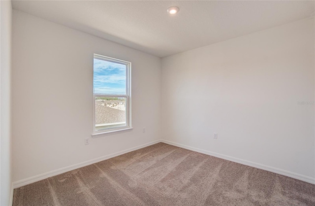carpeted empty room featuring baseboards