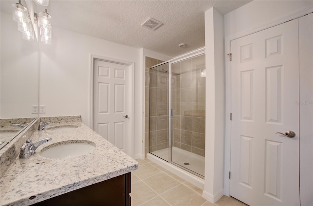 bathroom with tile patterned flooring, a stall shower, visible vents, and a sink