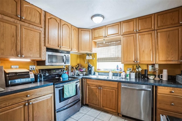 5224 29th Ave S, Gulfport, FL 33707 - kitchen featuring dark countertops, light tile patterned floors, appliances with stainless steel finishes, and a sink