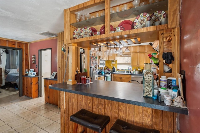 5224 29th Ave S, Gulfport, FL 33707 - kitchen featuring light tile patterned floors, a peninsula, open shelves, stainless steel appliances, and dark countertops