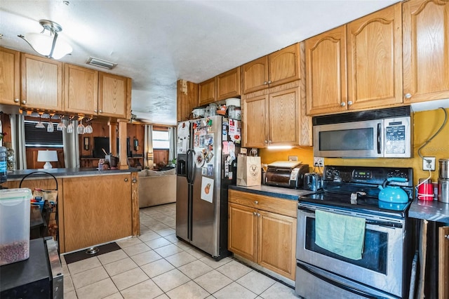 5224 29th Ave S, Gulfport, FL 33707 - kitchen featuring light tile patterned flooring, brown cabinets, appliances with stainless steel finishes, and dark countertops