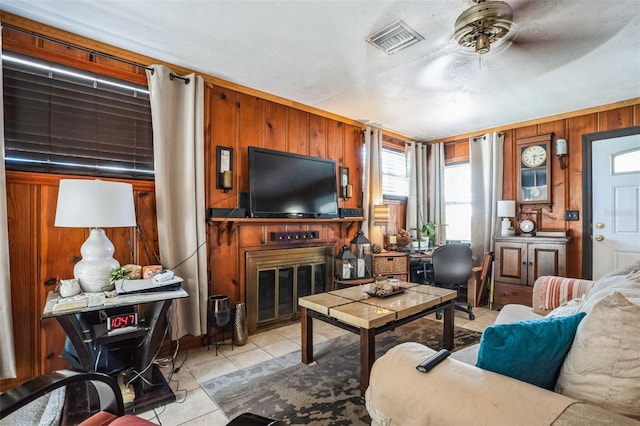5224 29th Ave S, Gulfport, FL 33707 - living area with visible vents, ceiling fan, wood walls, light tile patterned flooring, and a glass covered fireplace