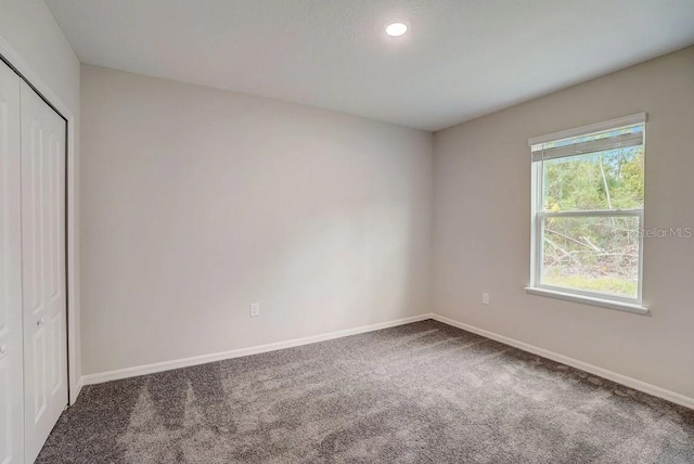 unfurnished bedroom featuring a closet, recessed lighting, baseboards, and carpet