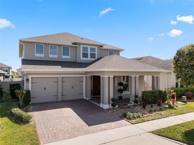 view of front of house with decorative driveway, a garage, roof with shingles, and stucco siding