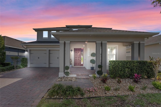 prairie-style house featuring stucco siding, decorative driveway, and a garage