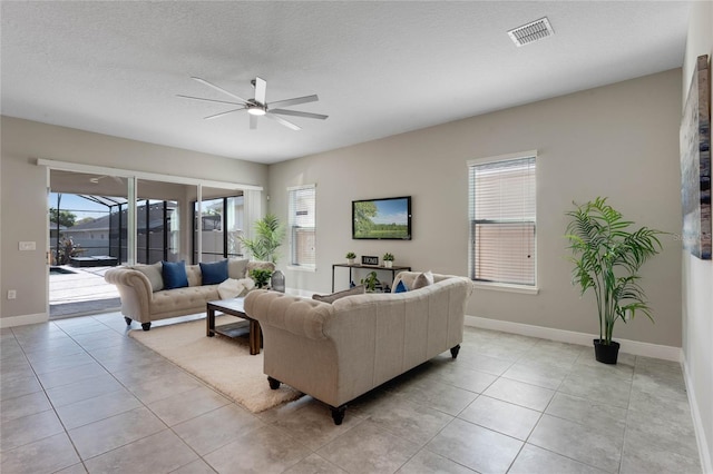 living area with visible vents, a wealth of natural light, and ceiling fan