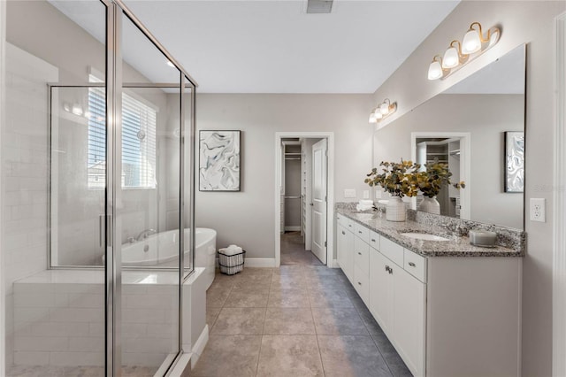 full bath with a walk in closet, a stall shower, a sink, double vanity, and a bath