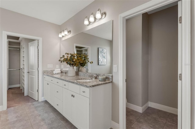 full bath featuring a sink, a walk in closet, and tile patterned floors