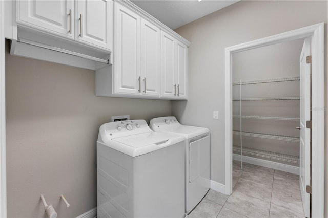 laundry area with light tile patterned floors, baseboards, cabinet space, and washing machine and dryer