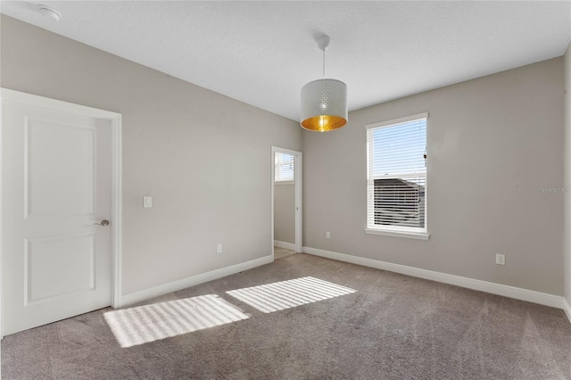 unfurnished bedroom with carpet, baseboards, and a textured ceiling