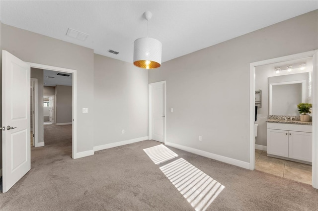unfurnished bedroom with connected bathroom, light colored carpet, visible vents, and baseboards