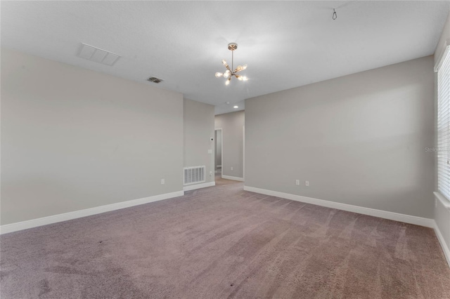 spare room with carpet, a notable chandelier, baseboards, and visible vents