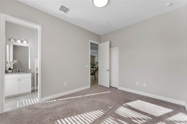 unfurnished bedroom with visible vents, light colored carpet, ensuite bath, and baseboards